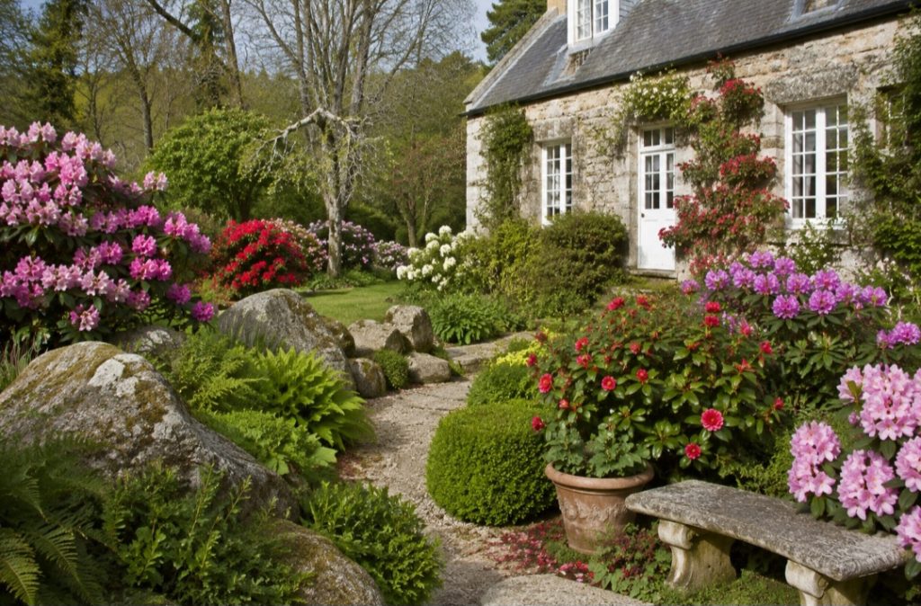 Jardin fleuri avec maison en pierre